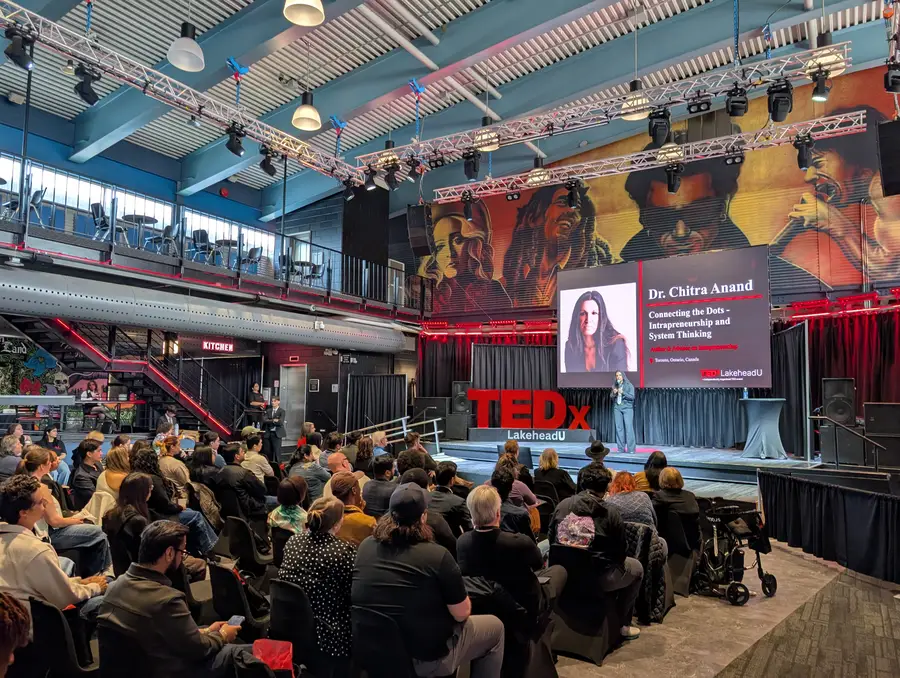 Dr. Chitra Anand on stage with her title slide
