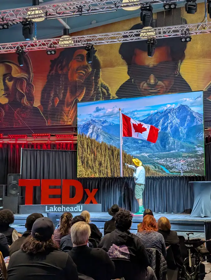 Stephen Ritz on stage in front of a Canadian flag slide